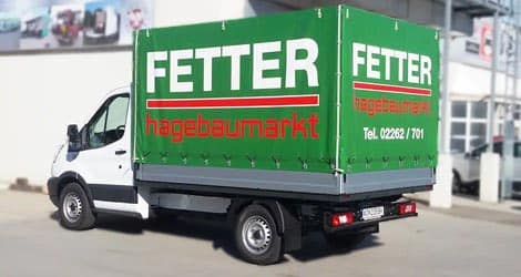 Ein robustes Iveco-Fahrzeug mit Pritschenaufbau und Plane, bereit für den Transport von Waren und Gütern.